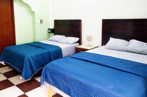 梅里达Casa NE的酒店客房,配有两张带蓝色床单的床