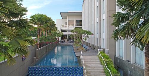 诗都阿佐Premier Place Surabaya Airport的棕榈树建筑中间的游泳池