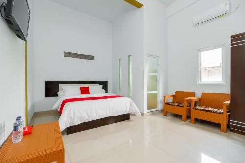 巨港RedDoorz Syariah near Simpang Sekip Palembang的一间白色卧室,配有一张床和两把椅子