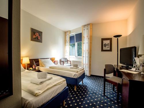 帕彭堡Parkhotel Papenburg的酒店客房设有两张床和电视。