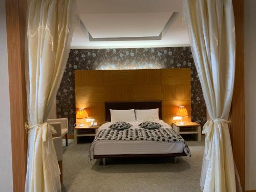阿克套大努尔广场酒店的一间卧室配有一张带两张桌子和两盏灯的床。