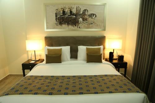 富查伊拉Uptown Hotel Apartment Fujairah By Gewan的一间卧室配有一张大床和两盏灯