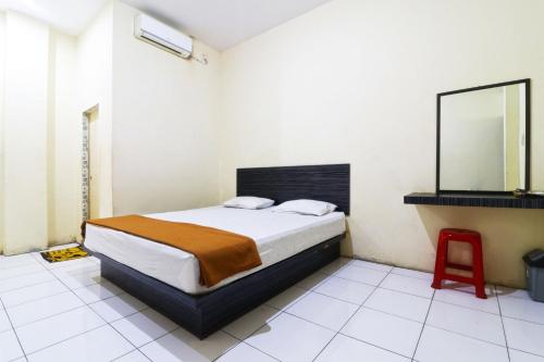 ParitGuest House Taman Sari Syariah的一间卧室配有一张带镜子和红色凳子的床
