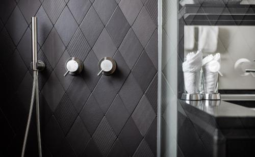 采尔马特Tradition Julen Hotel的浴室设有黑色瓷砖墙和镜子