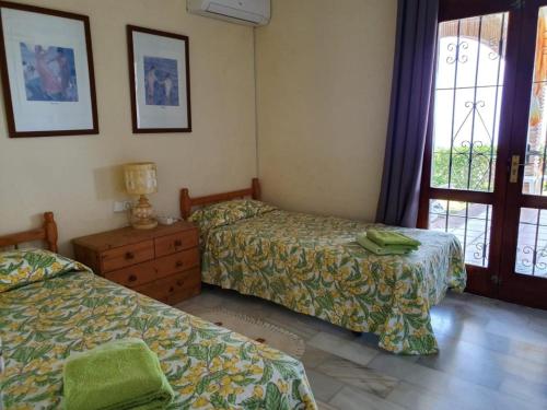 米哈斯Sea view villa with pool, near beach in Calahonda, Marbella area的一间卧室设有两张床、一个梳妆台和窗户。