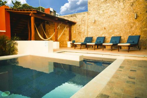 坎佩切Hotel Boutique Casa Don Gustavo, Campeche的一座带蓝色椅子的游泳池,位于大楼旁