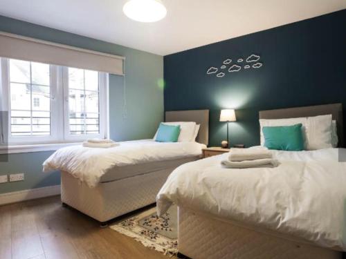 爱丁堡20/5 Timber Bush的一间卧室设有两张床和蓝色的墙壁