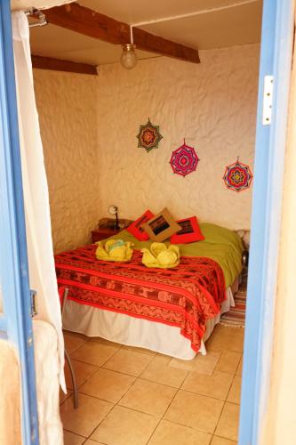 圣佩德罗·德·阿塔卡马提埃拉妈妈旅舍的一间卧室配有一张带红色毯子的床