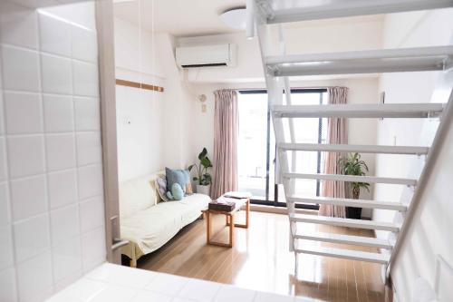 东京MINIMAL SHIMOKITA Stylish Loft or Studio Apt的梯子通往带沙发的客厅