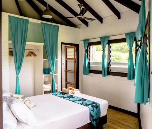 马太Vakanananu Retreat的一间卧室配有一张带蓝色窗帘的大床