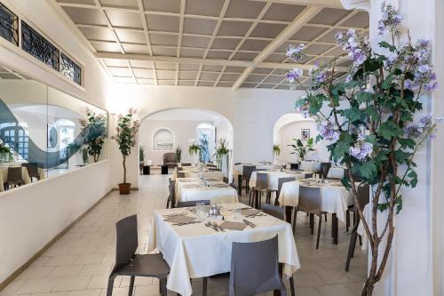 伊斯基亚温泉御苑酒店的餐厅设有桌椅和紫色鲜花