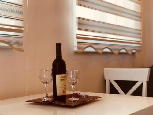 蒂瓦特Laguna apartment的桌子上放有一瓶葡萄酒和两杯酒