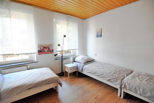 贝尔吉施格拉德巴赫Central Apartment Bergisch Gladbach的配有白色墙壁和木制天花板的客房内的两张床