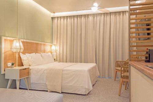 托罗尼Eco Green Residences & Suites的酒店客房带一张床、一张桌子和椅子