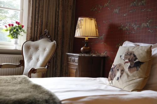 德吕特屯特罗斯的一间卧室配有一张带椅子和一盏灯的床