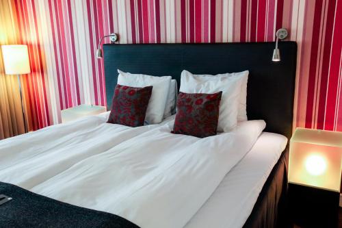 卡尔马威特第一酒店的一张带两个红色枕头的白色床