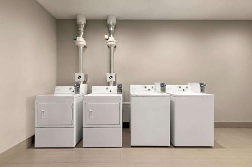 布伦瑞克La Quinta Brunswick/Golden Isles的客房内的一排白色洗衣机和烘干机
