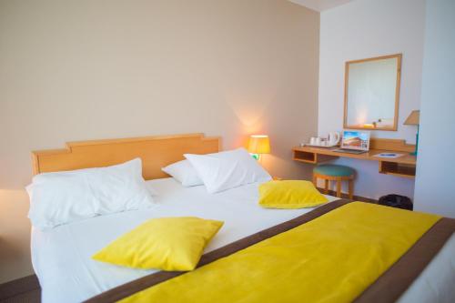 吕扎什格尔福蒙格力风酒店的一间卧室配有一张带黄色枕头的大床