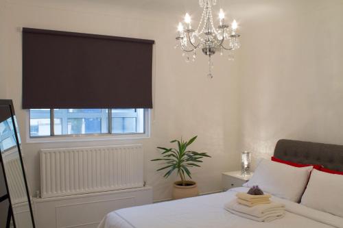 伦敦Baker Street Style的一间卧室配有一张带吊灯和窗户的床。