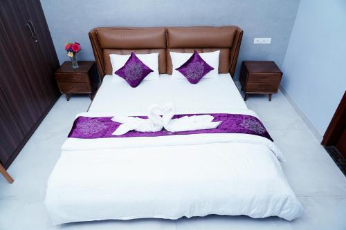 迈索尔UNNATHI SUITES的一间卧室配有一张铺有紫色和白色床单的床