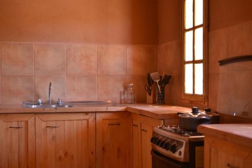 圣佩德罗·德·阿塔卡马卡萨斯月亮谷酒店的厨房配有木制橱柜、炉灶和水槽。