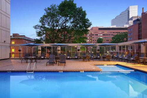 波士顿温德姆波士顿笔架山酒店的一个带桌椅和遮阳伞的游泳池