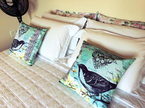多明戈斯马丁斯Eco Pousada Quaresmeiras的床上有两个枕头,上面有鸟儿