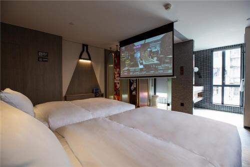 广州锋·态度酒店（广州火车站店）的一间卧室配有两张白色的床和电视
