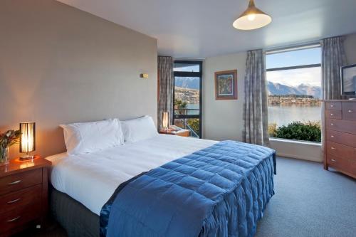 皇后镇三角帆湾公寓式酒店的一间卧室设有一张大床和一个大窗户
