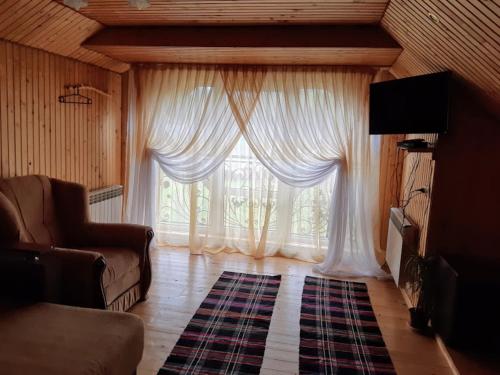 艾兹基Gostynna Rodyna的客厅设有大窗户和白色窗帘