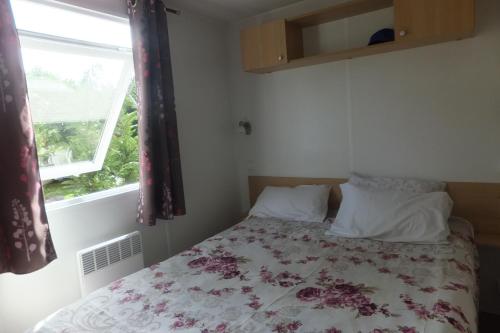 加斯泰Mobil Home Confortable 873 Camping Siblu La Reserve的一间卧室配有一张带花卉床罩的床和窗户。