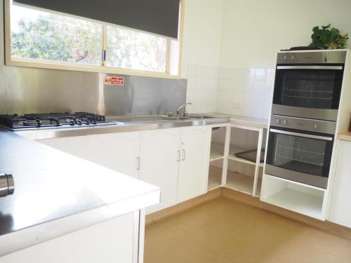 沃纳姆堡BIG4 Tasman Holiday Parks - Warrnambool的厨房配有白色橱柜和炉灶烤箱。