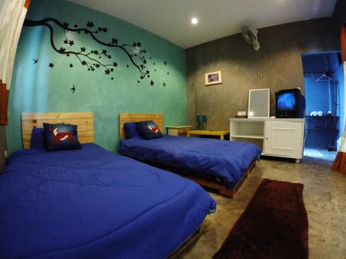 拜县帕怡度假酒店的一间卧室配有两张带蓝色床单和树壁画的床。