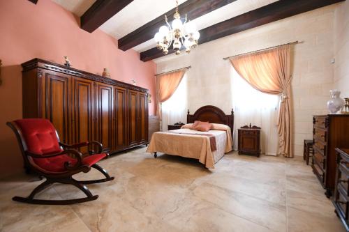 加拉Ir- Razzett t'Indri的一间卧室配有一张床、一把椅子和一个吊灯。