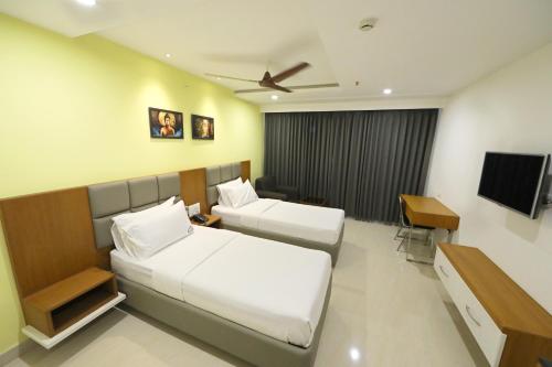 维杰亚瓦达Hotel Sri Ram Grand的酒店客房设有两张床和电视。