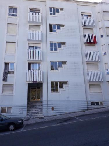 辛特拉Rio de Mouro Quartos的一座白色的公寓楼,前面设有停车位