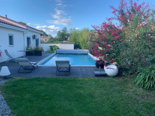 Orliénas乐克劳斯彭特酒店的庭院内的游泳池,带椅子和鲜花