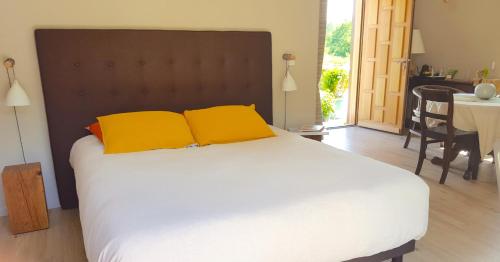 Saint-Pierre-AzifL'Herbe aux Vaches的一间卧室配有一张大床和两张黄色枕头
