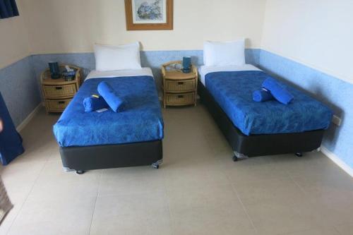 飞鱼湾日落酒店的配有两张床铺的蓝色床单和蓝色枕头