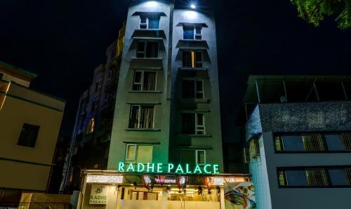 加尔各答Treebo Trend Radhe Palace的一座高大的建筑,晚上有标志