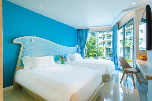 是拉差Centara Sonrisa Residences & Suites Sriracha的蓝色墙壁客房的两张床