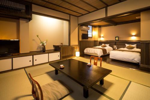 南小国町若叶日式旅馆的一间酒店客房,设有两张床、一张桌子和一台电视机