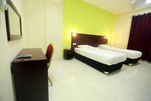 马斯喀特Al Dhiyafa Palace Hotel Apartments قصر الضيافة للشقق الفندقية的酒店客房配有两张床和一张书桌