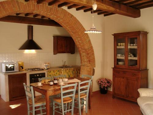 蒙特普齐亚诺弗拉特里亚圣贝内代托旅馆的厨房配有桌椅和拱门