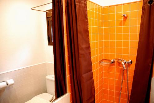 马德里加尔德拉韦拉Hostal El Cardenillo的浴室设有橙色瓷砖淋浴和卫生间