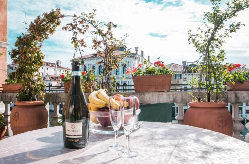 威尼斯Ca Zulian Venice - Grand Canal的桌子上放有一瓶葡萄酒和两杯酒