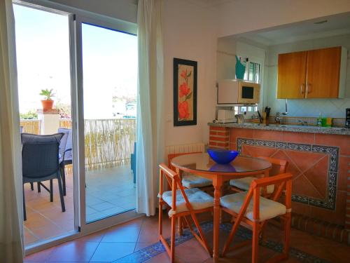内尔哈卡拉贝奥普拉亚别墅酒店的一间带桌椅的厨房和一间带阳台的厨房