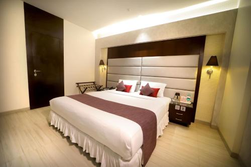 加尔各答南部广场酒店的卧室配有一张大白色的床和大床头板