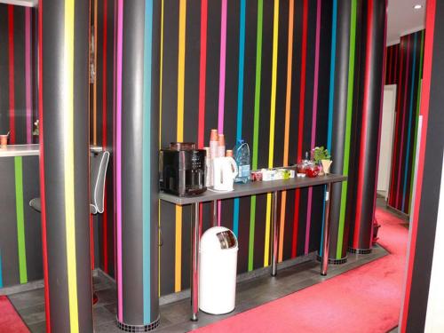 柏林Amaya Motel的一间拥有色彩缤纷的条纹墙壁和一张有家具的桌子的房间