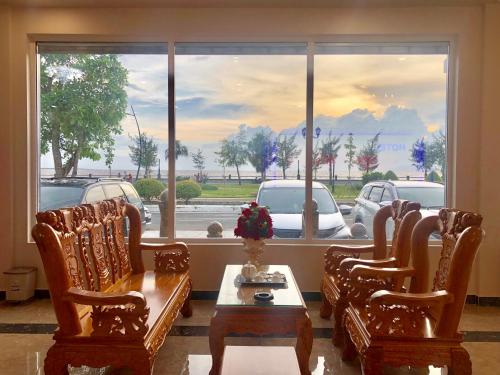 迪石Khách sạn Ngọc Thành 2的客厅配有椅子和桌子,设有大窗户